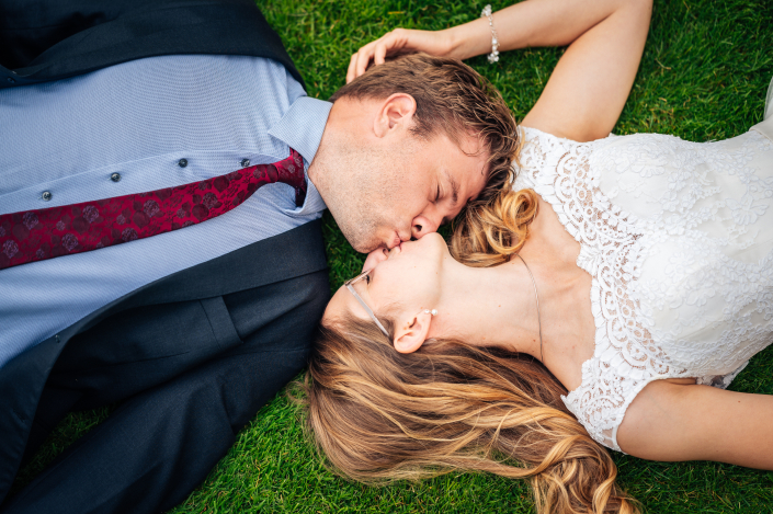 Brautpaarshooting Paar liegt auf den Rasen und küsst sich