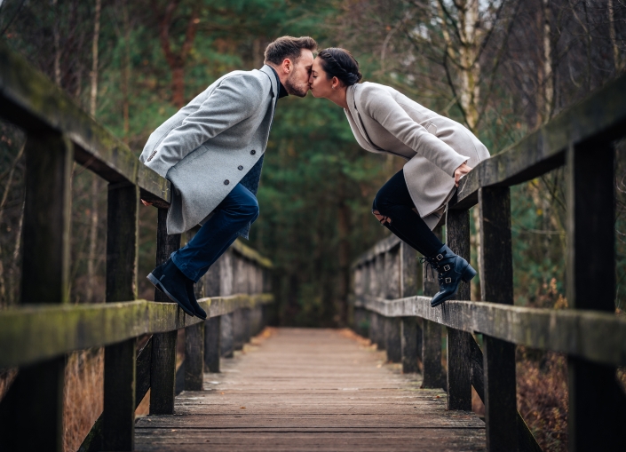 Paarhooting auf Brücke sitzend und küssen
