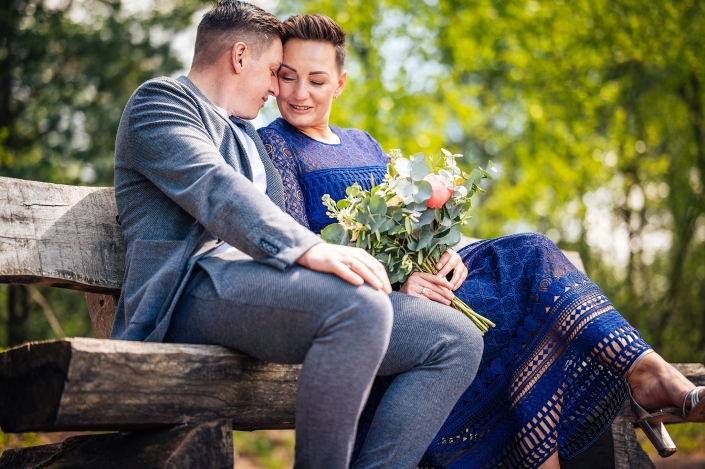 Brautpaar sitzt auf einer Holzbank, Stirn an Stirn