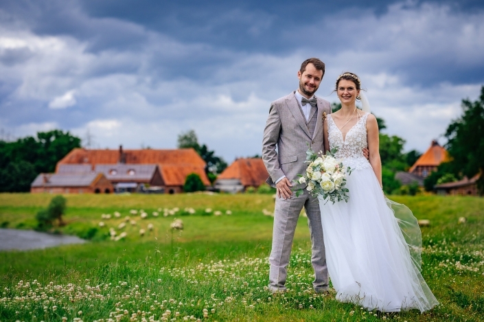 Brautpaarshooting dunkler Himmel, Wiese, Wasser und Schafe