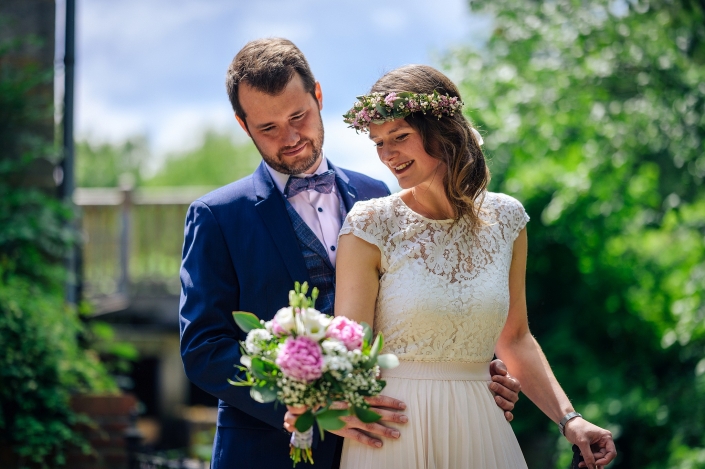 Brautpaarshooting vor Naturhintergrund mit Brautstrauß